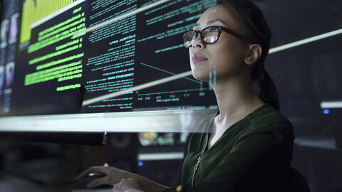 Woman in front of computer with NOC screens in background