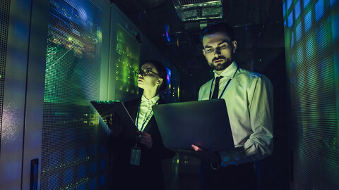 Man and woman in dark server room in green and blue light