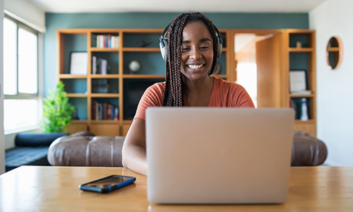 Young Black girl with long hair working on a laptop at a desk at home